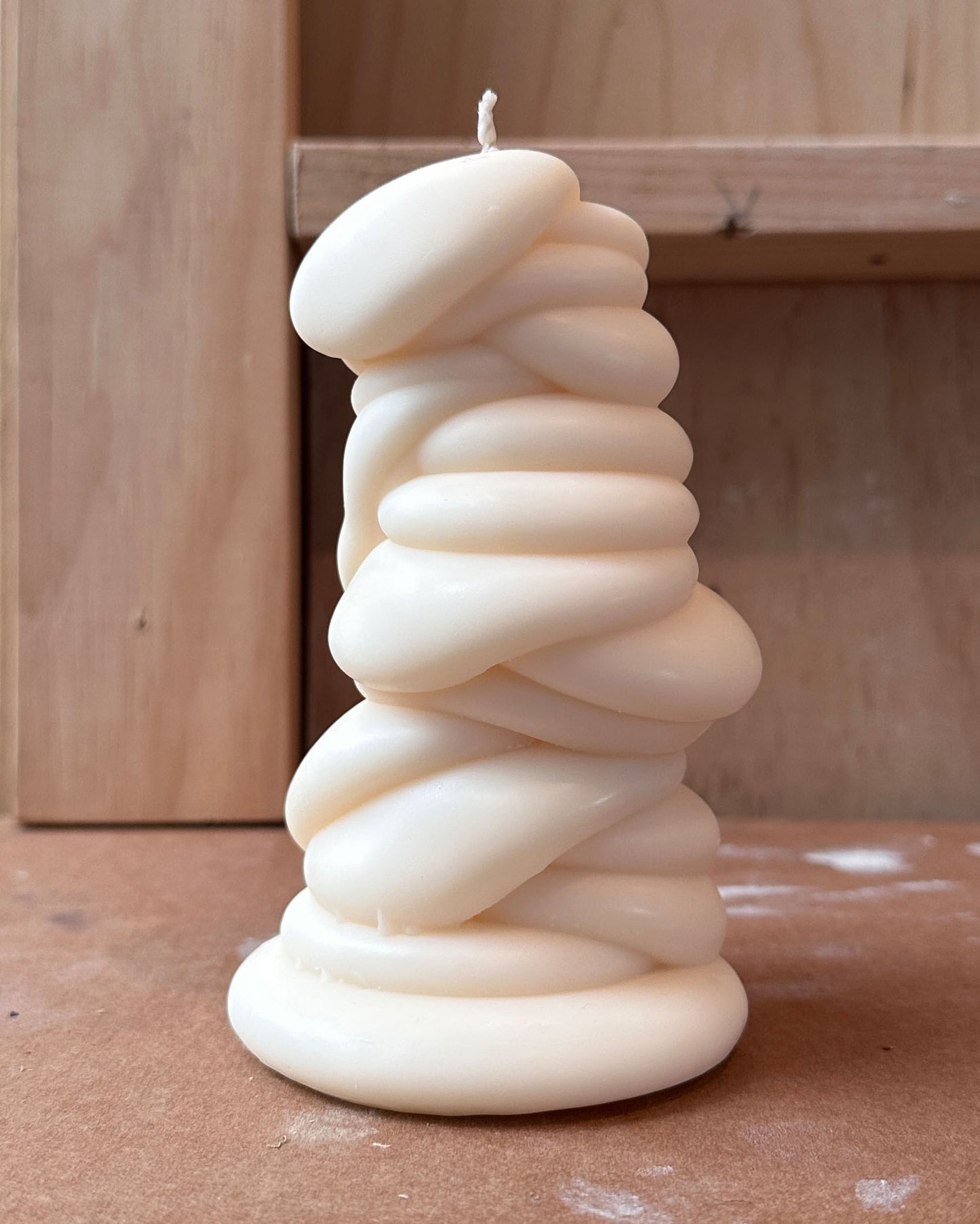 post objects White sculptural drippy shaped candle on a wooden surface